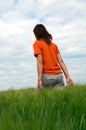 Girl walking in field of green wheat