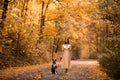 Girl is walking with her dog. Warm autumn. Portrait of a beautiful woman in a light dress. Beautiful young brunette Royalty Free Stock Photo