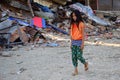 Girl walking pass collapsed building after earthquake disaster