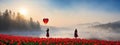 The girl walking in red tulip field, a heart shaped balloon ahead.concepts of lonely Valentine\'s Day Royalty Free Stock Photo