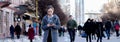 Girl walking and texting on the smart phone in the street wearing a gray coat, in the winter