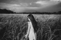 Girl walking on a wheat field holding wheat spike at beautiful sunset. Freedom and fresh air concept. Royalty Free Stock Photo