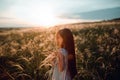 Girl walking on a wheat field holding wheat spike at beautiful sunset. Freedom and fresh air concept. Royalty Free Stock Photo