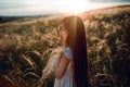 Girl walking on a wheat field holding wheat spike at beautiful sunset. Freedom and fresh air concept. Royalty Free Stock Photo