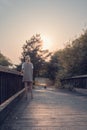 Girl walking on wooden bridge. Tranquility at sunset