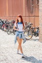 Girl walks along bicycle parking lot in sunny day