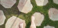 A girl walks barefoot on round stones path in the grass