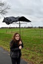 Girl walks with broken umbrella through the storm