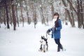 Girl walks with dog siberian husky in winter snowy forest