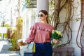 Girl walks down the street with a bouquet of flowers and coffee Royalty Free Stock Photo