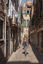 Girl walks down a sunlit alleyway in Venice
