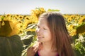 A girl walks through a field of sunflowers, looks inside a flower, looks tenderly, smiles. Royalty Free Stock Photo