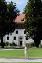 Girl walks in a garden on the background of an old house. A Ttouristic city in Europe