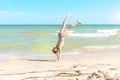 Girl walks on her hands on the sea beach on a summer sunny day Royalty Free Stock Photo