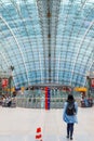 A girl walks inside a futuristic glass structure of the Frankfurt Airport train station with the Squaire business center.