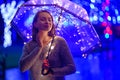 A girl walks through the night city with lights. Rainy. With an umbrella with lights Royalty Free Stock Photo