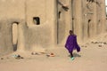 A girl walks past a mosque in a village near Djenne, Mali