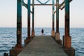 The girl walks on the pier in sunny weather and admires the sea scenery Royalty Free Stock Photo