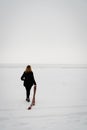 Girl walks on a snow-covered lake. Sad mood in black clothes. Royalty Free Stock Photo