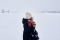 Girl walks through a snowstorm and looks at an old abandoned water intake on a frozen river Royalty Free Stock Photo