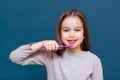 Girl wants to brush out dropping milk teeth on a blue background. The concept of oral hygiene and milk teeth in children