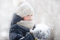 A girl in warm clothes and a hat walks in a snow-covered winter park