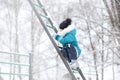 A girl in warm clothes and a hat walks in a snow-covered winter park