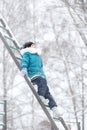 A girl in warm clothes and a hat walks in a snow-covered winter park