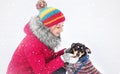 A girl in warm clothes and a hat walks in a snow-covered winter park