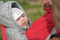 A girl in warm clothes on the street. A young and happy mother holds a baby in her arms, smiles and rejoices. Street in winter,