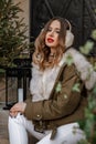 Girl warm fur headphones red lips.Beautiful portrait of woman in fur headphones. Attractive caucasian woman sits on a
