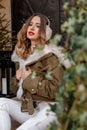 Girl warm fur headphones red lips.Beautiful portrait of woman in fur headphones. Attractive caucasian woman sits on a