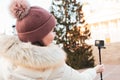 A girl in a warm hat, a winter day, shoots a video, a Christmas tree. Helsinki Royalty Free Stock Photo