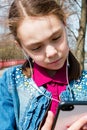 Girl in warm sunny weather on the street with headphones listening to music in the gadget close-up Royalty Free Stock Photo