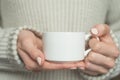 Girl in warm sweater is holding white mug in hands.. Mockup for winter gifts design Royalty Free Stock Photo