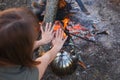 Girl warms her hands over the kettle by the fire Royalty Free Stock Photo