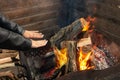 Girl warms up near open fire. Woman holds hands above flame to toast herself. Burning woods logs and charcoal are in barbecue