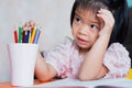 Girl was sitting and listening to the adults teach her homework and she played the wooden color in the white glass.