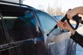 Girl washes a black SUV with a high-pressure car wash. Soap foam and water on the machine. Self-service car wash. A young woman wa Royalty Free Stock Photo