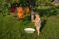 Girl washes clothes by hand in a basin in the backyard where a mongrel cat walks Royalty Free Stock Photo