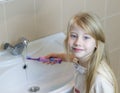 A girl washes an electric toothbrush after brushing her teeth. Royalty Free Stock Photo