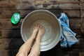 girl washes her feet in a basin of water on the wooden floor at home, foot care, wash feet at home, hygiene, swim Royalty Free Stock Photo