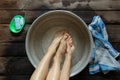 girl washes her feet in a basin of water on the wooden floor at home, foot care, wash feet at home, hygiene, swim Royalty Free Stock Photo