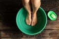 Girl washes her feet in a green bowl on the wooden floor of the house, foot care