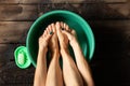 Girl washes her feet in a green bowl on the wooden floor of the house, foot care