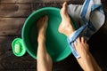 Girl washes her feet in a green bowl on the wooden floor of the house, foot care