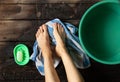 Girl washes her feet in a green bowl on the wooden floor of the house, foot care