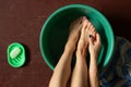 Girl washes her feet in a green bowl on the wooden floor of the house, foot care