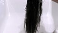 Girl washes her hair. Long dark hair. Water pours on the hair and head. Washing the head and hair