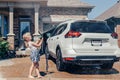 girl washing car on driveway in front house on sunny summer day Royalty Free Stock Photo